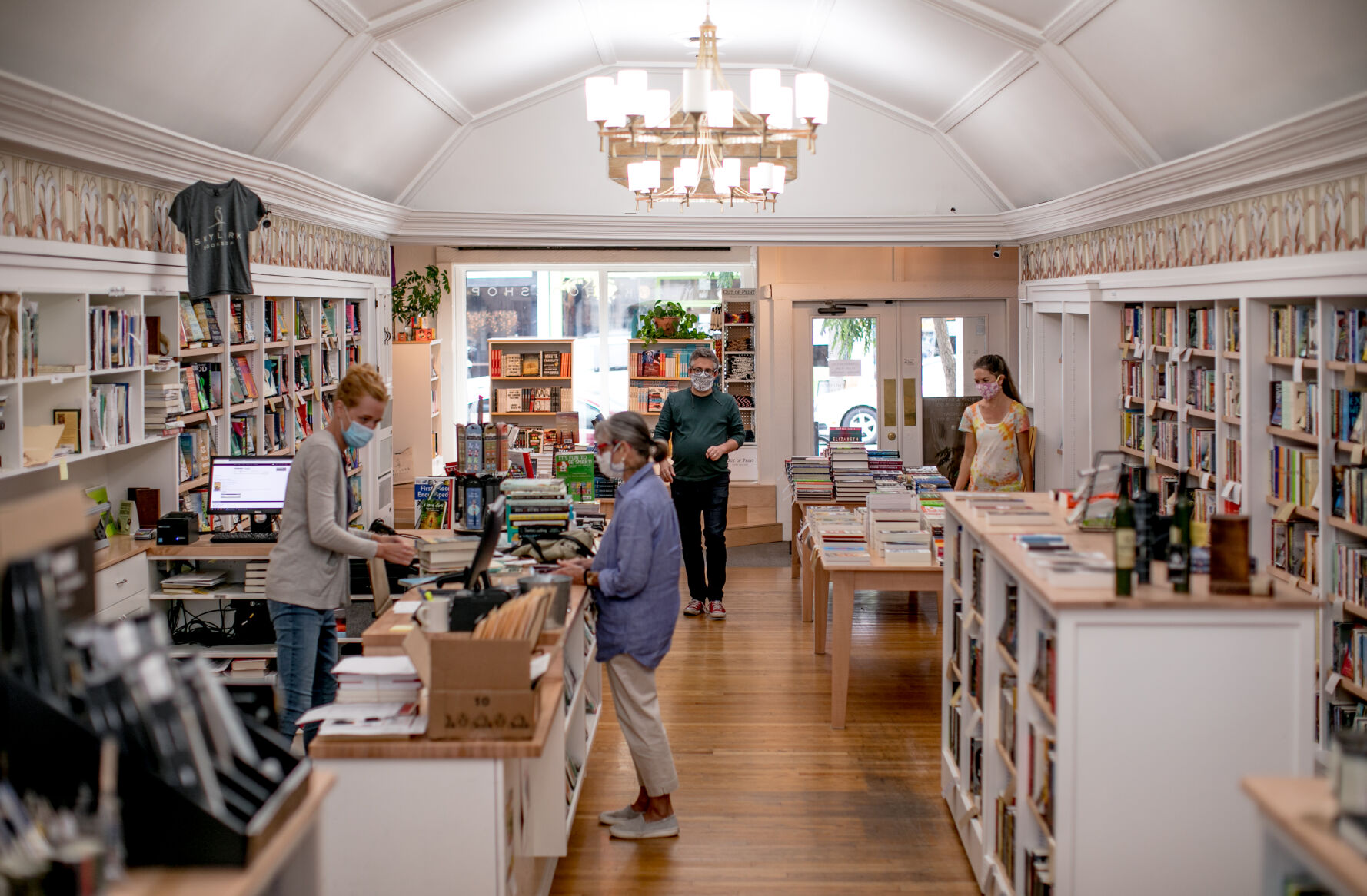 As one customer finishes her purchases, Alex George, center, chats with a new customer